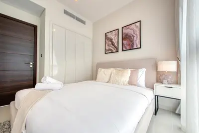 a white bedroom with a large bed and a table at Spell-binding 3BR Townhouse at DAMAC Hills 2 Dubailand by Deluxe Holiday Homes in Dubai