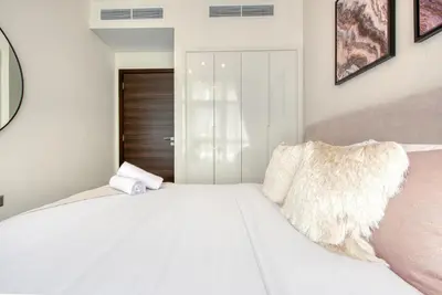 a white bedroom with a large white bed at Spell-binding 3BR Townhouse at DAMAC Hills 2 Dubailand by Deluxe Holiday Homes in Dubai