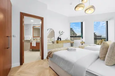 a white bedroom with a bed and a bathroom at Luxury 2BR with Skyline and Sea Views, Near Burj Khalifa & Dubai Mall in Dubai