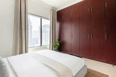 a bedroom with brown cabinets and a large window at Frank Porter - Time Place in Dubai