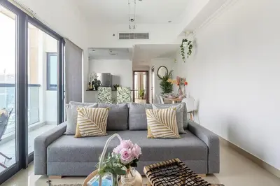 a living room with a gray couch and large windows at Frank Porter - Time Place in Dubai