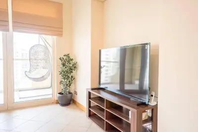a living room with a large flat screen tv at Premium 4BR Apt Pool Palm Beach Club Dubai in Dubai