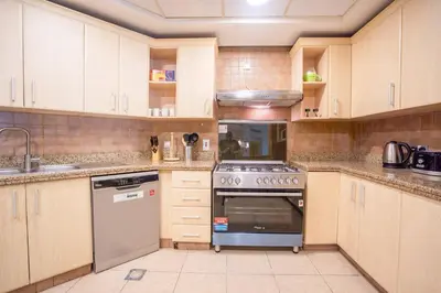 a kitchen with wooden cabinets and a stove at Premium 4BR Apt Pool Palm Beach Club Dubai in Dubai