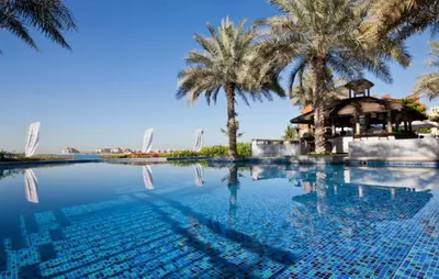 a swimming pool with palm trees and a gazebo at Premium 4BR Apt Pool Palm Beach Club Dubai in Dubai