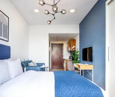 a bedroom with a large bed and a blue wall at Silkhaus modish studio with Burj Khalifa view, pool access in Dubai