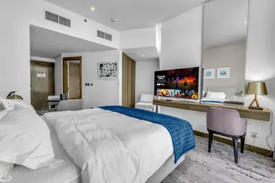 a bedroom with a large white bed and a desk at Luxury Aparthotel Prive in Dubai