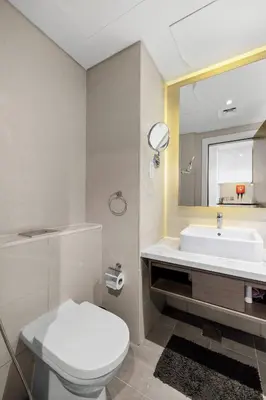 a bathroom with a toilet and a sink and a mirror at Luxury Aparthotel Prive in Dubai