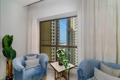 a living room with blue chairs and a large window at USMANS 4BDRM JBR Sadaf Next to Ritz Carlton Walk Daily Housekeeping JBR in Dubai