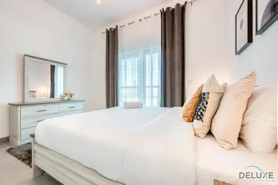 a white bedroom with a large bed and a window at Whimsical 2BR at Bella Rose Barsha South by Deluxe Holiday Homes in Dubai