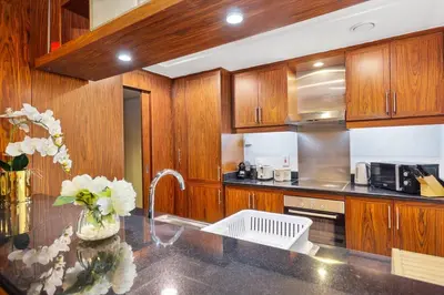 a kitchen with wooden cabinets and a counter top at Walk to Burj Khalifa from this 2BR with Skyline Balcony View in Dubai