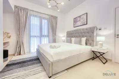 a white bedroom with a bed and a large window at Exquisite 2BR at Zahra Breeze Dubailand by Deluxe Holiday Homes in Dubai