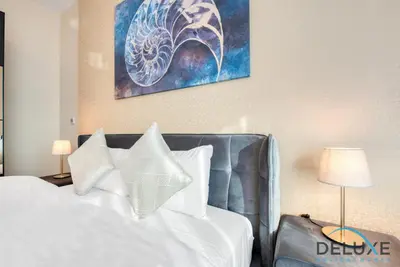a bedroom with a bed with white sheets and pillows at Short Distance from Global Village & Other Major Attractions Studio Unit, Al Jawhara Tower, Jumeirah Village Triangle by Deluxe Holiday Homes in Dubai