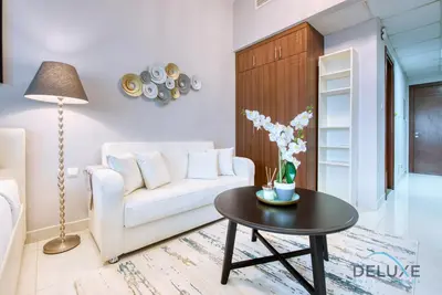a living room with a white couch and a table at Serene Studio in Elite Residences 4 Sports City by Deluxe Holiday Homes in Dubai