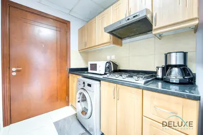a kitchen with a stove and a washing machine at Serene Studio in Elite Residences 4 Sports City by Deluxe Holiday Homes in Dubai