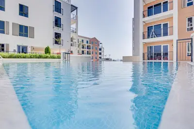 a swimming pool in front of two apartment buildings at Lovely sea view apt La Cote 1 La Mer 1min to beach in Dubai