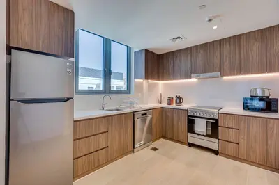 a kitchen with wooden cabinets and a stainless steel refrigerator at Lovely sea view apt La Cote 1 La Mer 1min to beach in Dubai
