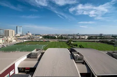 a train station with a green field and a city at Emirates Sports Hotel, Dubai Sports City in Dubai