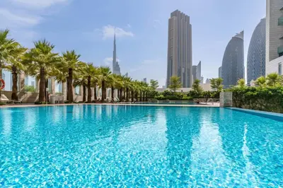 a large swimming pool with palm trees in a city at Silkhaus comfy DIFC studio with Burj Khalifa view in Dubai