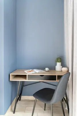 a desk with a chair in front of a blue wall at Silkhaus comfy DIFC studio with Burj Khalifa view in Dubai