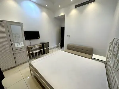 a living room with a bed and a tv at Economical Rooms for rent in Dubai in Dubai