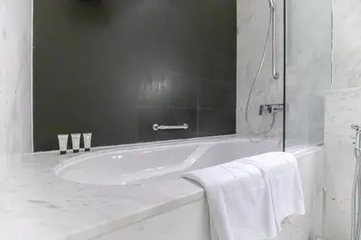 a white bathroom with a tub and a shower at Emaar Fashion Avenue - Formerly Address Dubai Mall Four Apple in Dubai