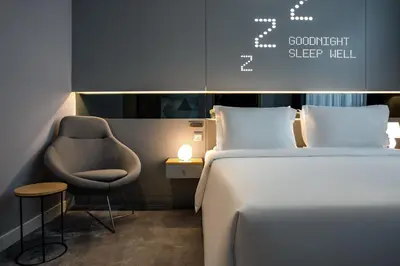 a bedroom with a bed and a chair next to a bed at Studio M Al Barsha Hotel by Millennium in Dubai