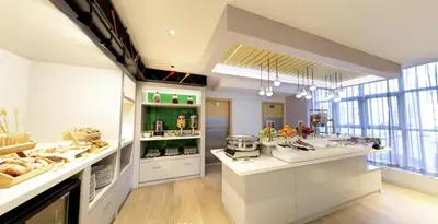 a large kitchen with white counters and a large window at Studio M Al Barsha Hotel by Millennium in Dubai