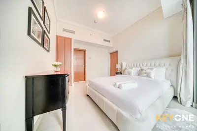 a white bedroom with a large bed and a television at Captivating Sky & Sea Views in Two Bedroom Suite in Dubai