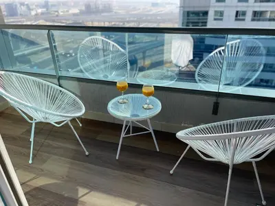 three chairs and two wine glasses on a balcony at Luxury Studio Apartment Close to JBR Beach&Yacht Club&Metro-Available Airport Shuttle in Dubai