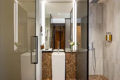 a bathroom with two sinks and a shower with a mirror at Voco Dubai Monaco, The Heart of Europe by IHG-Adult only in Dubai