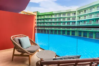 a balcony with a wicker chair and a swimming pool at Voco Dubai Monaco, The Heart of Europe by IHG-Adult only in Dubai