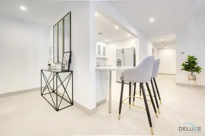 a white kitchen with a table and a stool at Spacious 3BR Apartment with Assistant Room in Sadaf 5 JBR by Deluxe Holiday Homes in Dubai