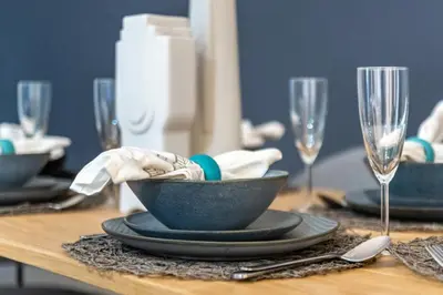 a wooden table with a bowl and plates and wine glasses at The Smart Concierge - Plaza residence in Dubai