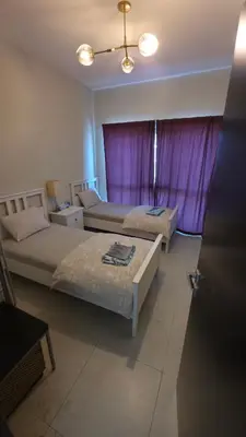 a bedroom with two beds and a purple curtain at Elegant and comfortably furnished 2BRH apartment in a quiet area! in Dubai