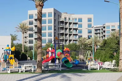 a playground in front of a large building at Elegant and comfortably furnished 2BRH apartment in a quiet area! in Dubai
