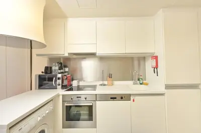 a white kitchen with white cabinets and a microwave at Emaar Fashion Avenue - Formerly Address Dubai Mall Residence in Dubai