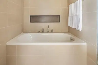 a white bath tub in a tiled bathroom at Frank Porter - BLVD Heights T1 in Dubai