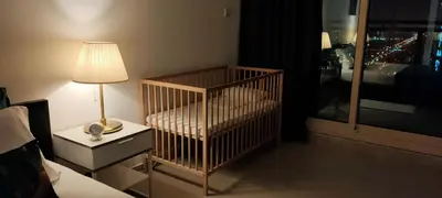 a crib in a bedroom with a lamp and a window at Nice 2 bedroom apartment-minimum 5 night in Dubai