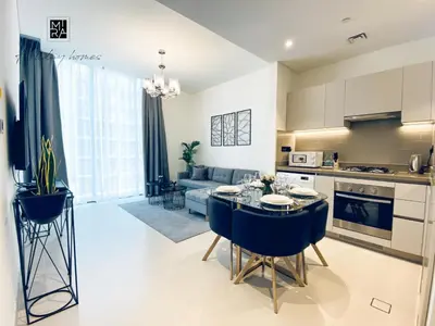 a kitchen and living room with a table and chairs at Mira Holiday Homes - Newly Furnished 1 bedroom in Creek Vista Tower B Sobha Hartland in Dubai