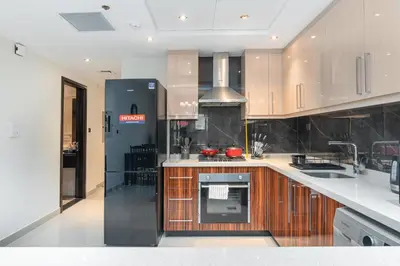 a kitchen with white counter tops and wooden cabinets at White Sage - Elite Residence 1 bedroom in Dubai