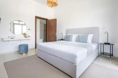 a white bedroom with a large bed and a mirror at Frank Porter - Executive Tower F in Dubai