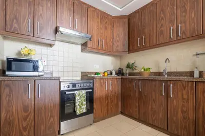 a kitchen with wooden cabinets and a stove top oven at Frank Porter - Executive Tower F in Dubai