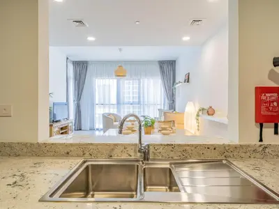 a kitchen with a sink and a living room at Charming Tropical Apartment Minutes To Dubai Mall in Dubai