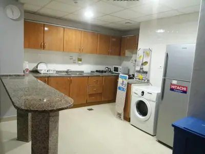 a kitchen with a refrigerator and a washing machine at AlBarsha 1 Hostel by PHM in Dubai