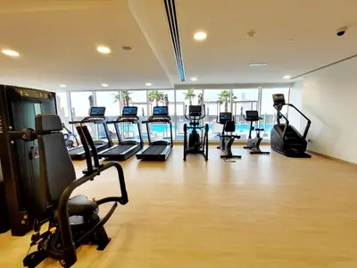 a gym with a row of treadmills and exercise bikes at Bloom Height Tower in Dubai