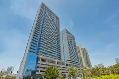a tall building with palm trees in front of it at Bloom Height Tower in Dubai
