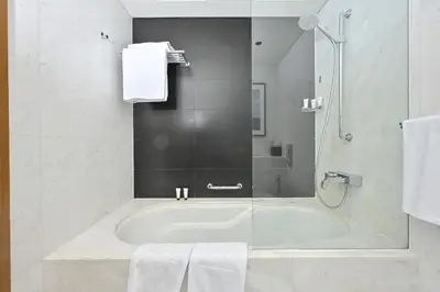 a bathroom with a tub and a shower with towels at FAHH - Spacious Studio in Emaar Fashion Avenue in Dubai
