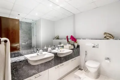 a white bathroom with two sinks and a toilet at The Smart Concierge - Amna Tower in Dubai
