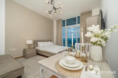 a living room with a bed and a table with flowers at Modern & Stylish Studio in JVT in Dubai