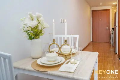 a table with plates and a vase with flowers on it at Modern & Stylish Studio in JVT in Dubai